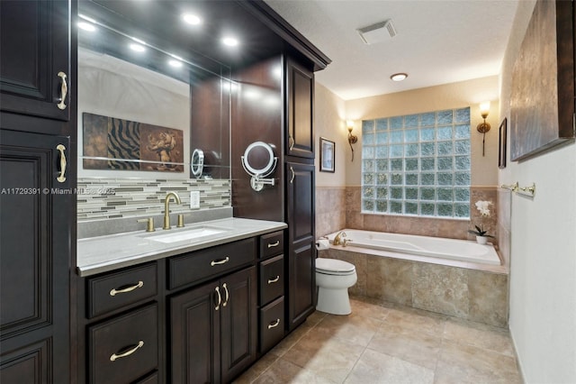 bathroom featuring tiled bath, toilet, and vanity