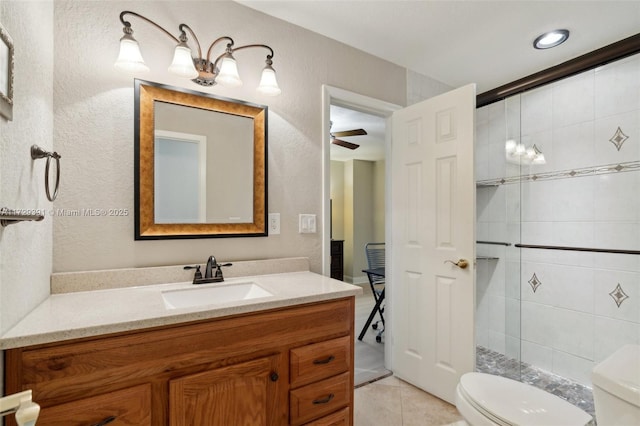 bathroom featuring vanity, toilet, a tile shower, and tile patterned flooring