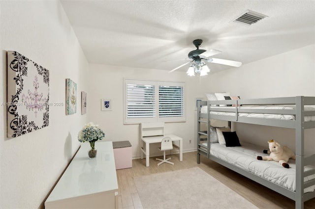 bedroom with ceiling fan, light hardwood / wood-style flooring, and a textured ceiling