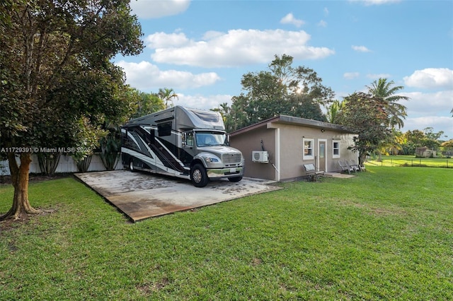 rear view of house with a wall mounted AC and a yard