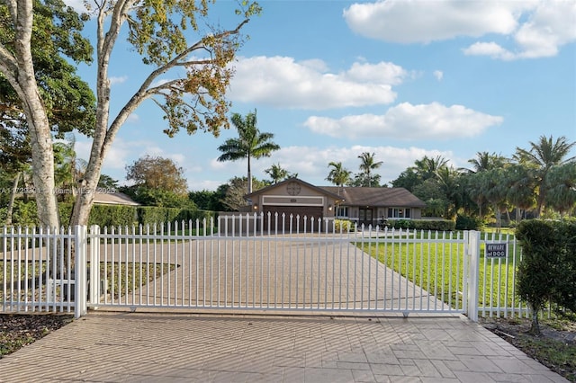 view of gate with a garage and a lawn