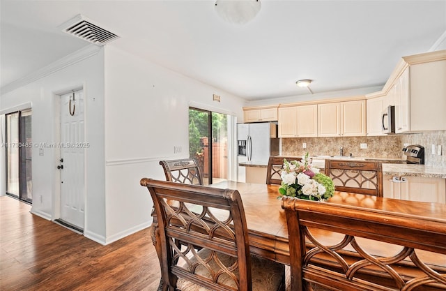 interior space with tasteful backsplash, appliances with stainless steel finishes, dark wood-type flooring, and cream cabinetry