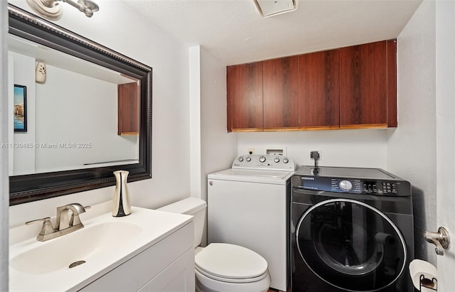 clothes washing area featuring sink, a textured ceiling, and washer and clothes dryer