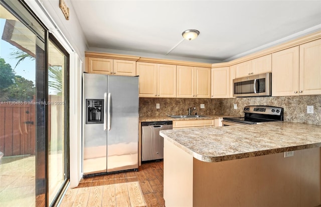 kitchen featuring sink, kitchen peninsula, stainless steel appliances, light hardwood / wood-style floors, and decorative backsplash