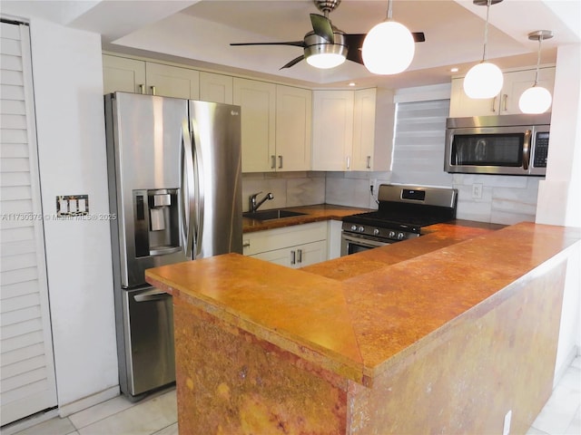 kitchen featuring pendant lighting, sink, appliances with stainless steel finishes, backsplash, and kitchen peninsula