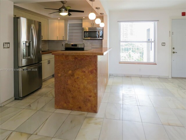 kitchen featuring tasteful backsplash, ceiling fan, appliances with stainless steel finishes, and hanging light fixtures