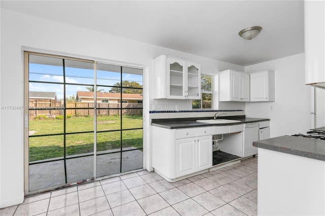 kitchen with tasteful backsplash, dishwasher, light tile patterned floors, white cabinets, and sink