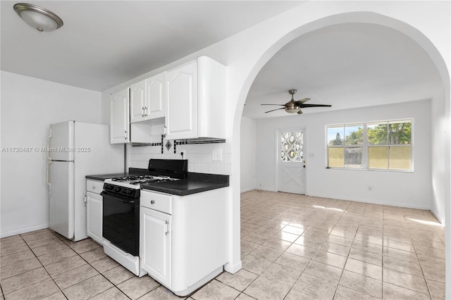 kitchen with gas stove, white cabinetry, white refrigerator, backsplash, and light tile patterned floors