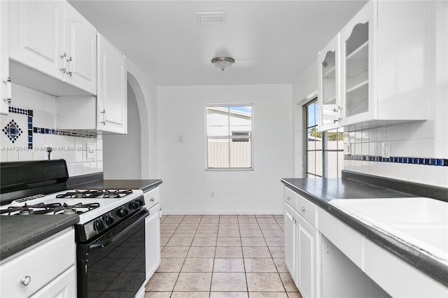 kitchen with backsplash, white cabinetry, light tile patterned floors, and gas stove