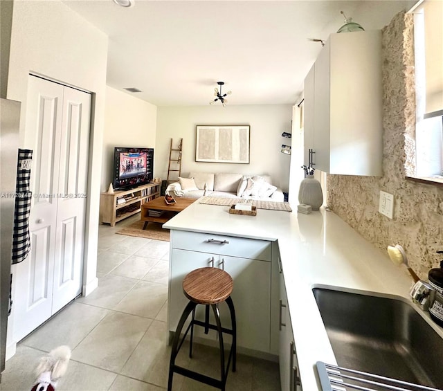 kitchen with decorative backsplash, sink, light tile patterned floors, and kitchen peninsula