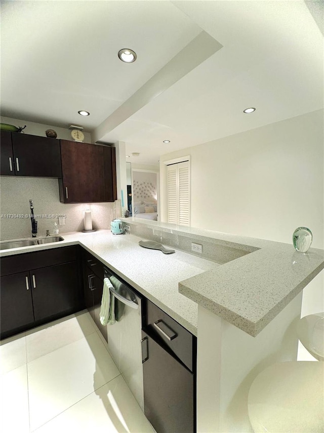 kitchen with sink, light stone countertops, kitchen peninsula, and dishwasher