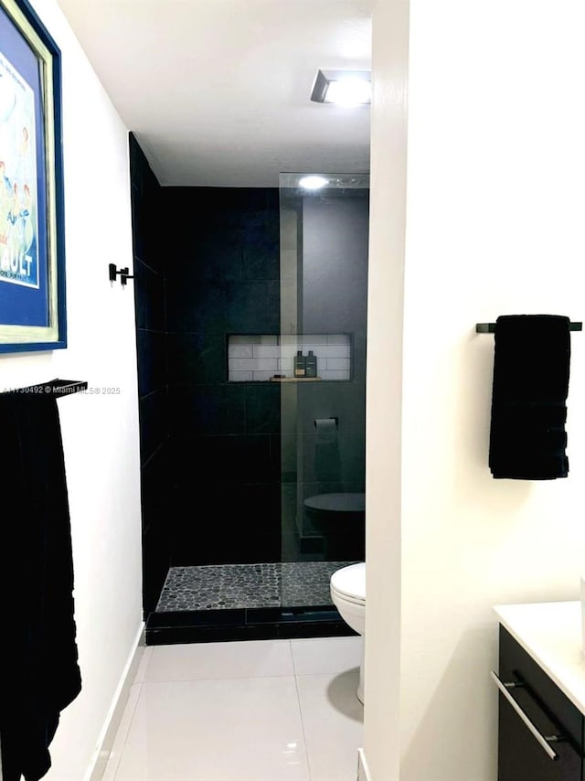 bathroom featuring vanity, tile patterned floors, toilet, and tiled shower