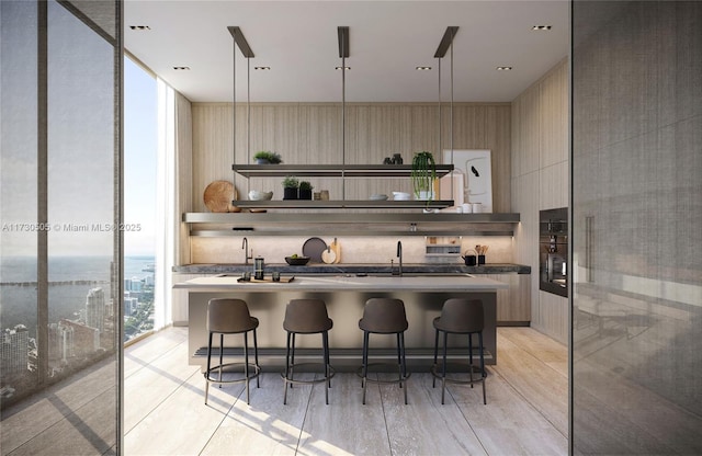 kitchen with floor to ceiling windows, decorative light fixtures, a breakfast bar, and an island with sink