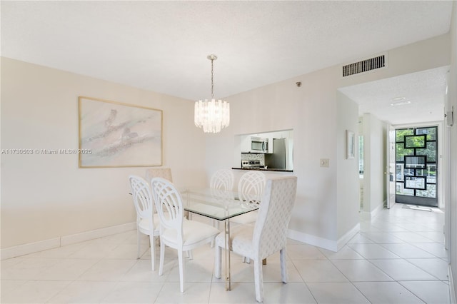 tiled dining space featuring a chandelier and a textured ceiling