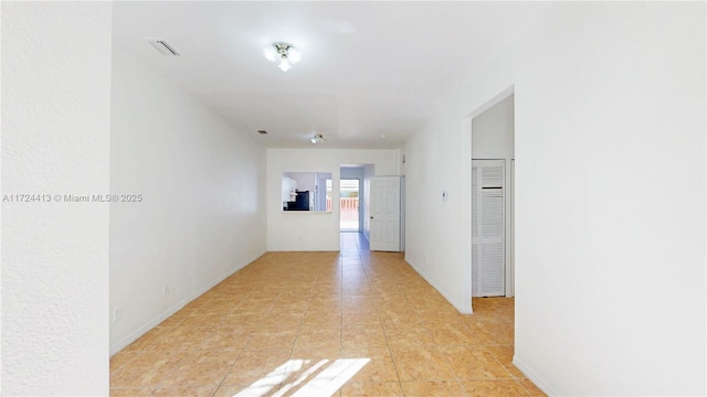 hall featuring light tile patterned floors, baseboards, and visible vents