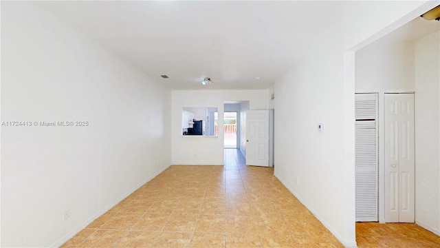 corridor with light tile patterned floors, visible vents, and baseboards