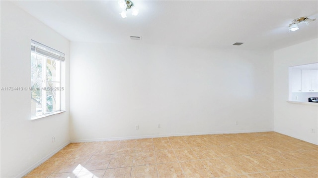 empty room featuring light tile patterned floors, baseboards, and visible vents