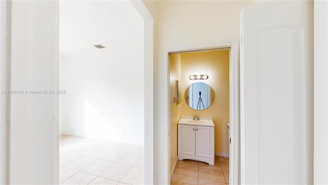 corridor featuring light tile patterned floors, visible vents, and a sink