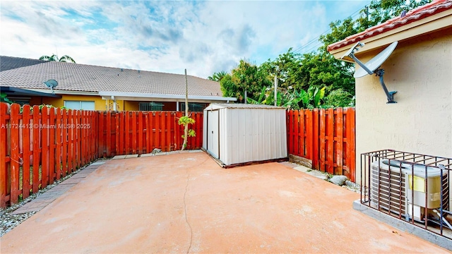 view of patio / terrace with an outdoor structure, a fenced backyard, and a shed