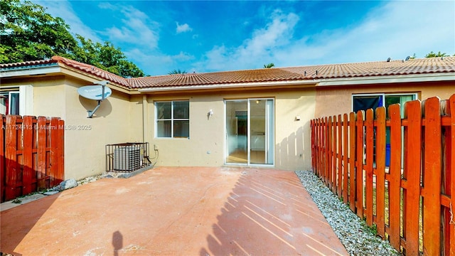 back of property with a tiled roof, stucco siding, a patio, and fence