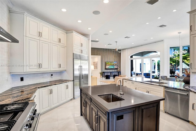 kitchen featuring decorative backsplash, sink, decorative light fixtures, an island with sink, and high quality appliances