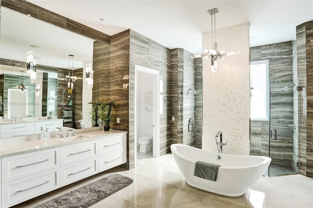 full bathroom featuring a notable chandelier, toilet, tile walls, vanity, and separate shower and tub