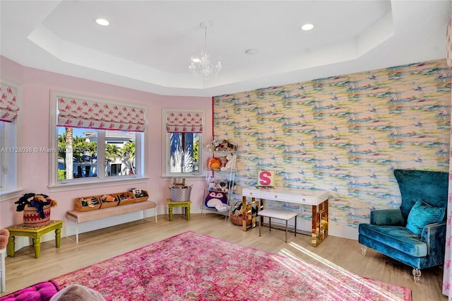 rec room with a raised ceiling, an inviting chandelier, and wood-type flooring