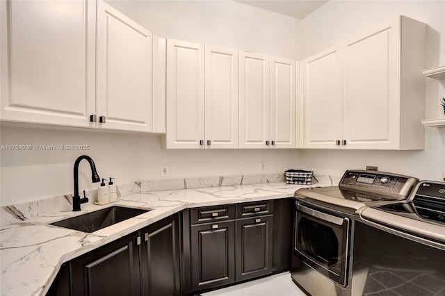 laundry room featuring sink, washer and clothes dryer, and cabinets