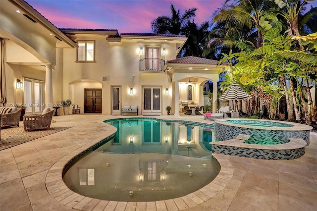 pool at dusk with an in ground hot tub, a patio area, ceiling fan, and an outdoor hangout area