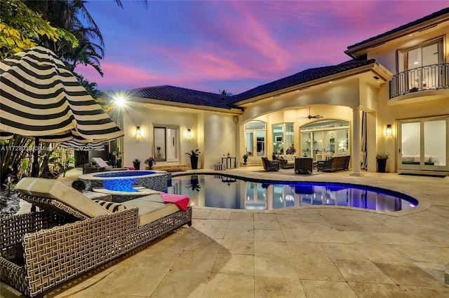 pool at dusk with an in ground hot tub, a patio area, outdoor lounge area, and ceiling fan