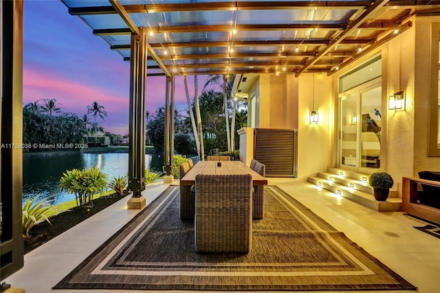 patio terrace at dusk with a water view and a pergola