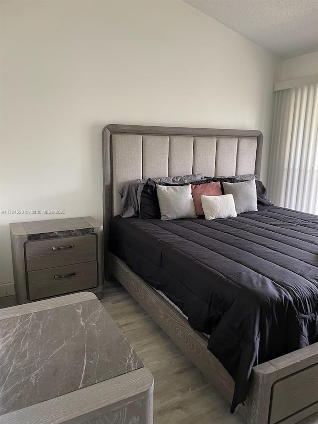 bedroom with light hardwood / wood-style floors and a textured ceiling