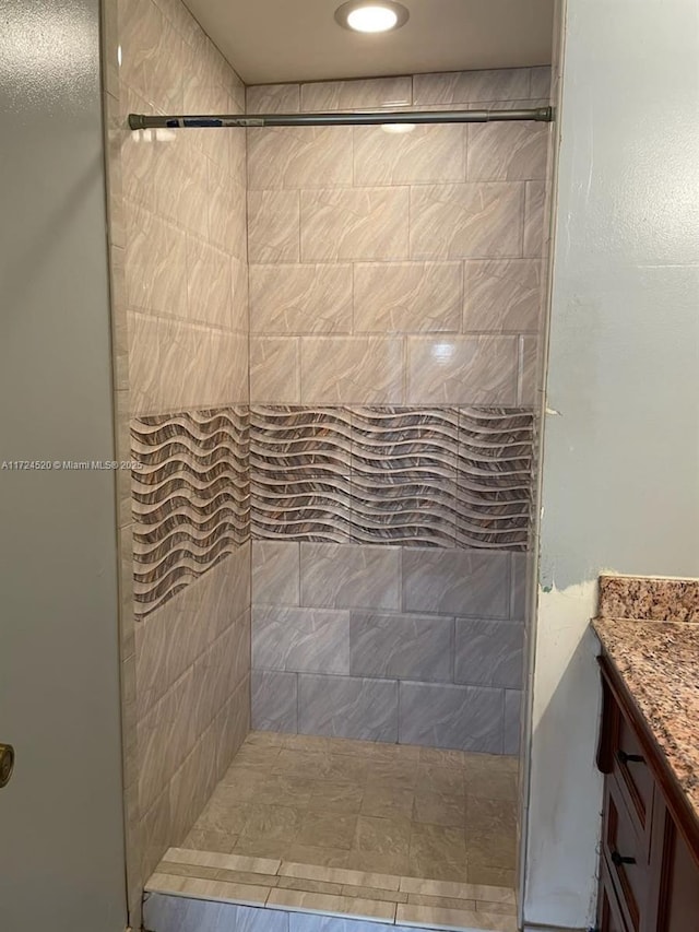 bathroom with tiled shower and vanity