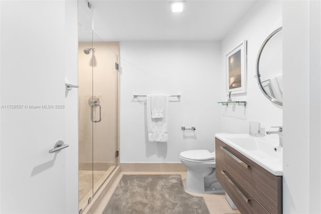 bathroom featuring vanity, a shower with shower door, and toilet