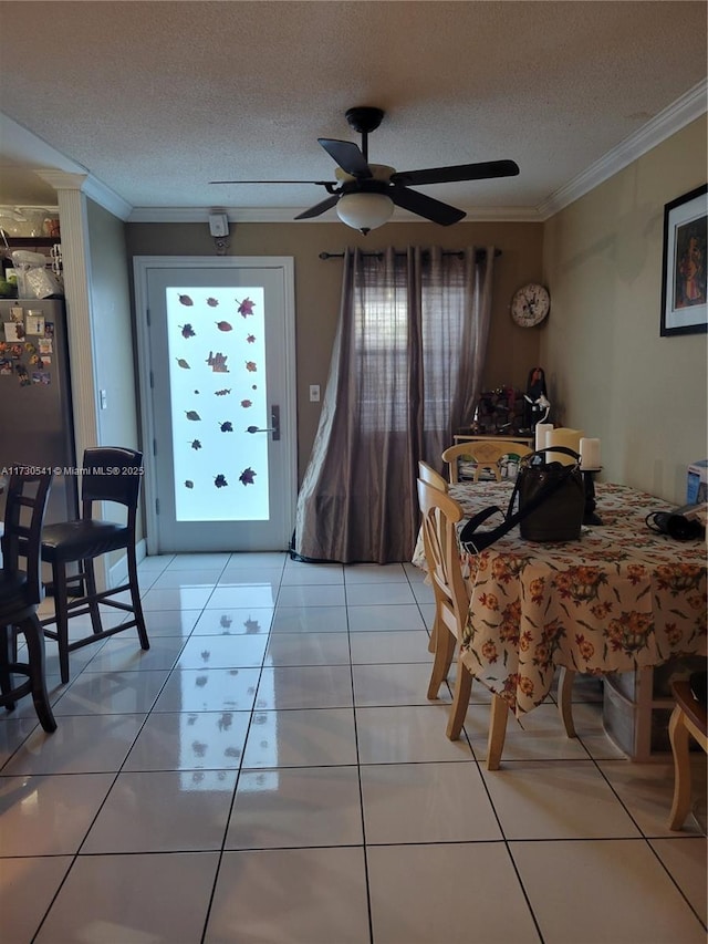 tiled dining room with ceiling fan, a textured ceiling, and ornamental molding