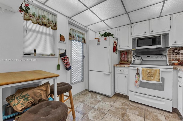 kitchen featuring white cabinetry, backsplash, white appliances, and a paneled ceiling