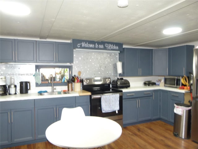 kitchen featuring sink, decorative backsplash, dark wood-type flooring, stainless steel appliances, and blue cabinetry