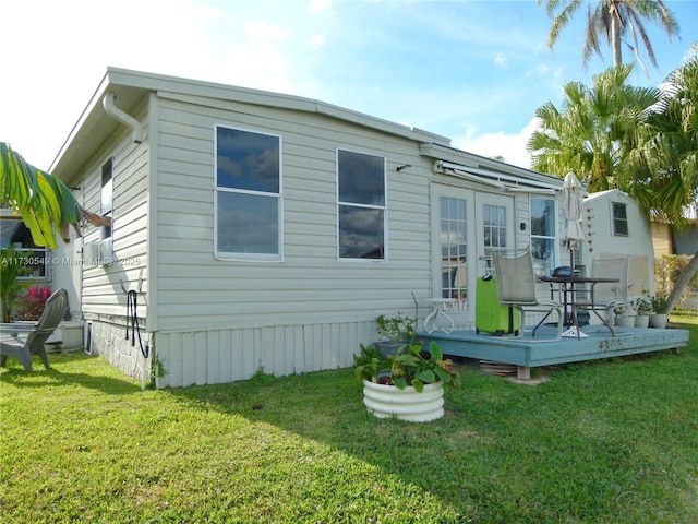 back of house featuring a wooden deck, a lawn, and french doors