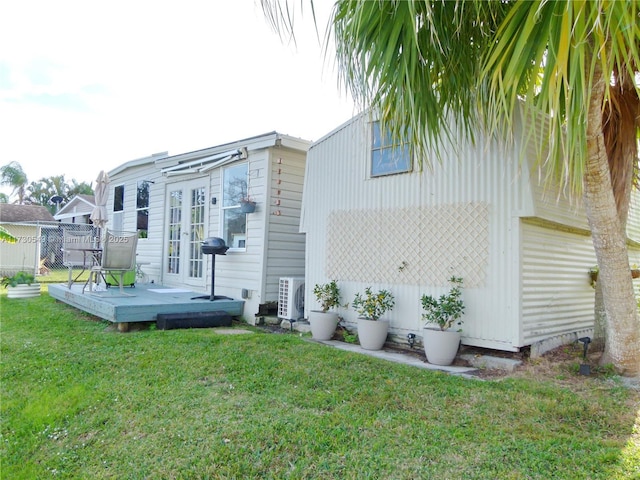 back of property with a wooden deck, a yard, and ac unit