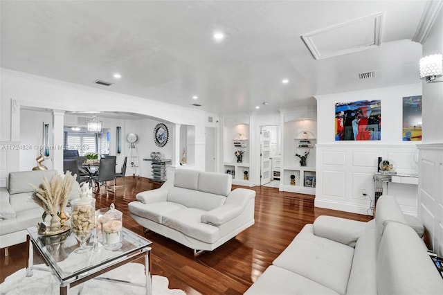 living room with built in features, hardwood / wood-style floors, ornate columns, and ornamental molding