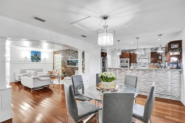 dining space with hardwood / wood-style flooring and ornate columns