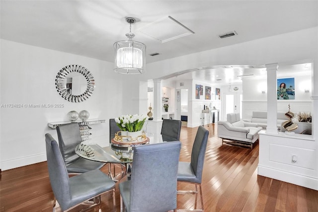 dining space with decorative columns and dark wood-type flooring