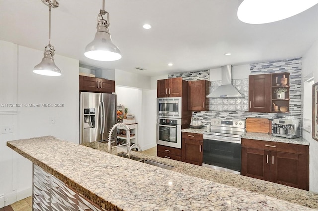 kitchen featuring wall chimney exhaust hood, stainless steel appliances, decorative backsplash, sink, and hanging light fixtures