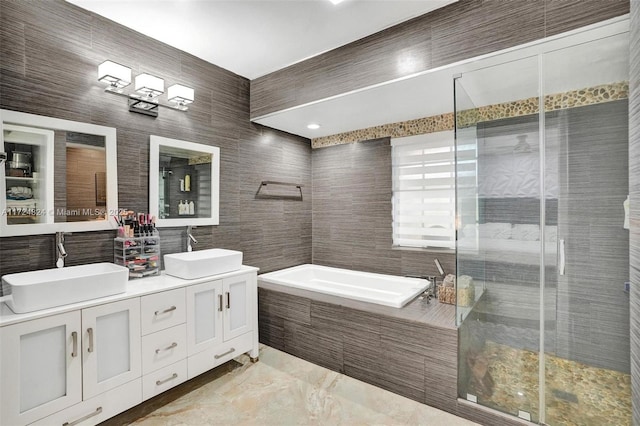 bathroom featuring separate shower and tub, tile walls, and vanity