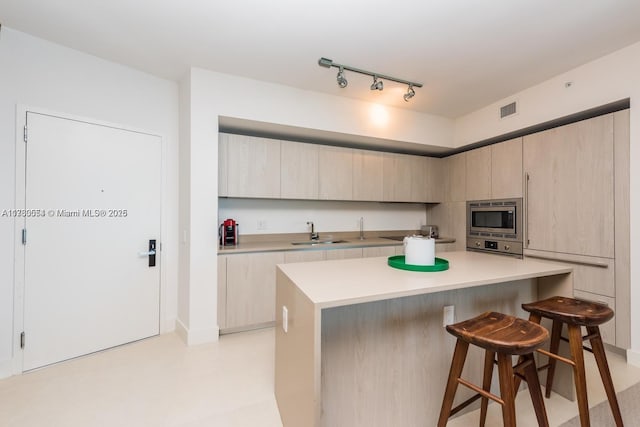 kitchen featuring light brown cabinets, a breakfast bar area, a center island, and stainless steel microwave