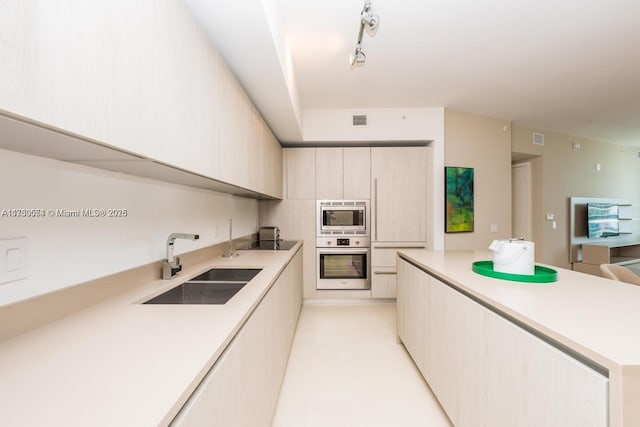 kitchen featuring sink, appliances with stainless steel finishes, and track lighting