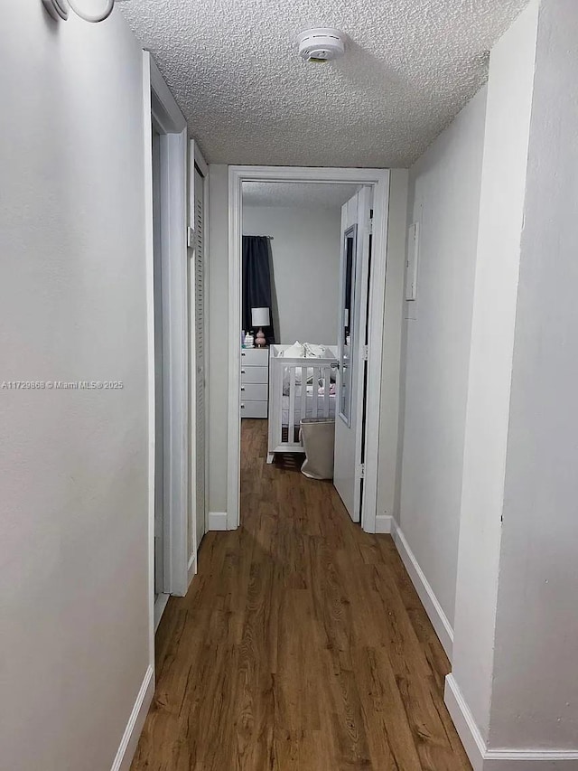 hall with a textured ceiling and dark hardwood / wood-style floors