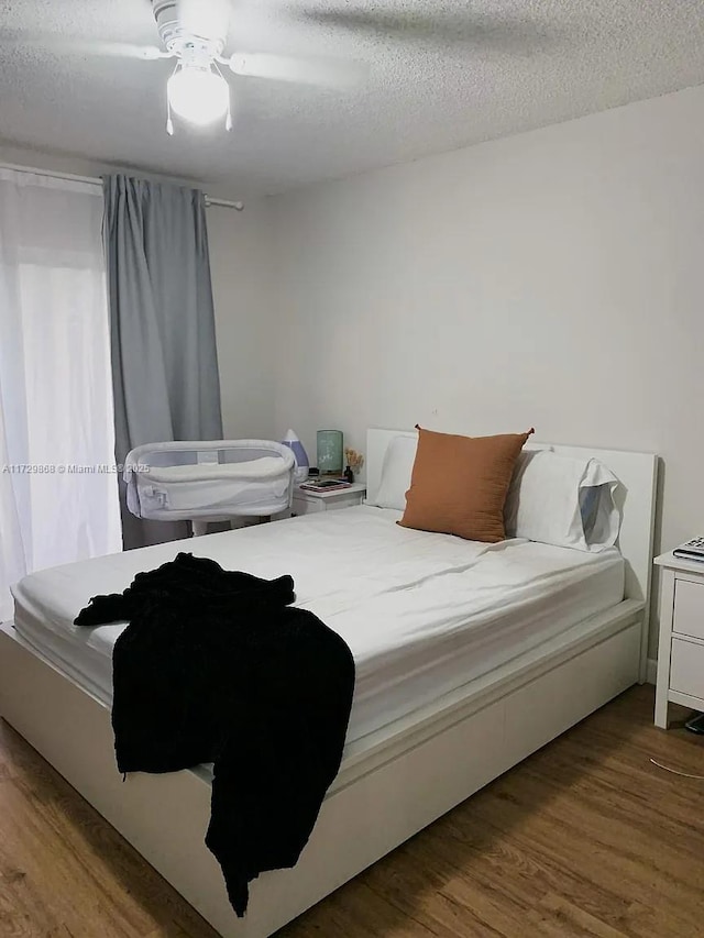 bedroom with ceiling fan, hardwood / wood-style floors, and a textured ceiling