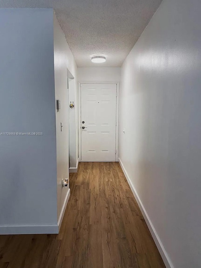 hallway featuring a textured ceiling and wood-type flooring