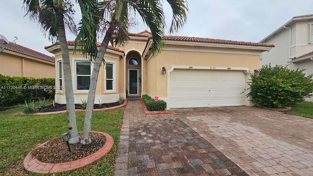 mediterranean / spanish-style house with a garage and a front lawn